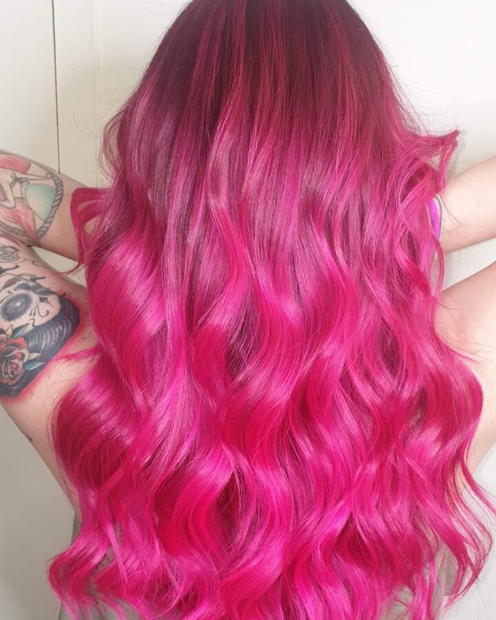 Cabello largo con coloración fucsia vibrante y ondas definidas